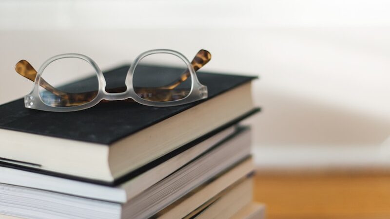 clear framed eyeglasses on top of pile of books