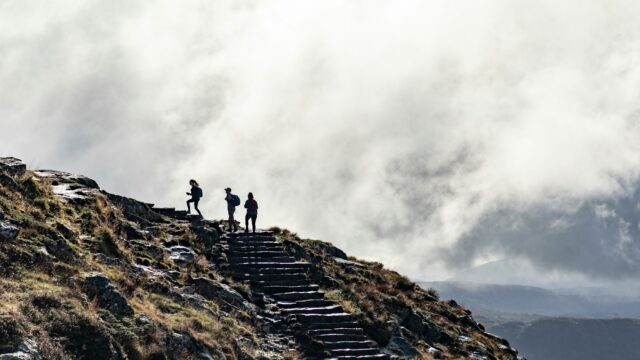 person standing on rocky mountain under cloudy sky during daytime
